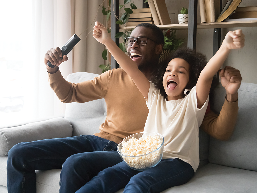 father and child cheering on the sofa